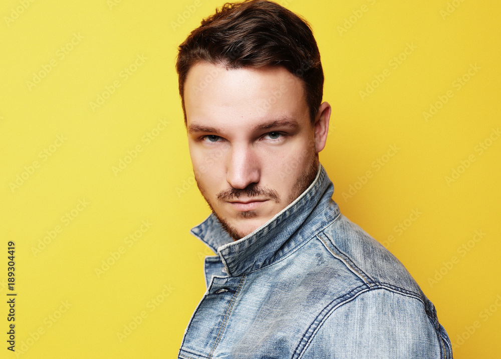 Fototapeta premium Portrait of a handsome young man, fashion model. Posing over yel