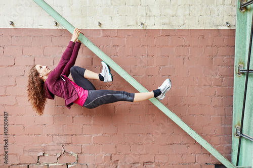 Junge Frau beim schwierigen Fassadenklettern