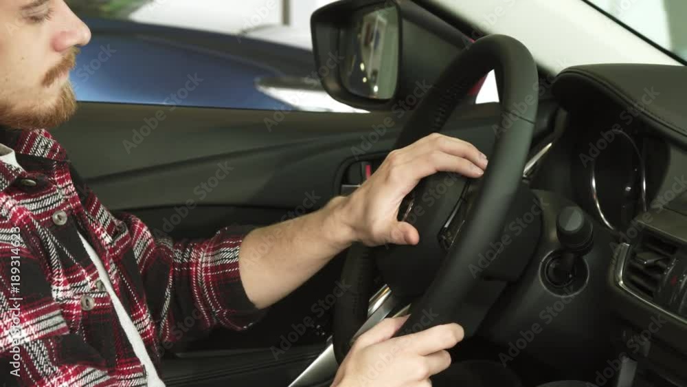 Cropped shot of a bearded man sitting in a car holding the steering wheel Cropped shot of a bearded man sitting in a car holding the steering wheel