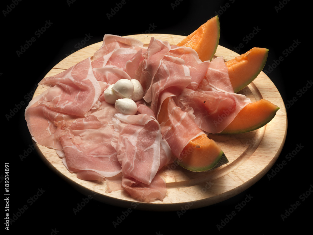 raw parma ham and melon on a wood dish raw parma ham and melon on a wood dish