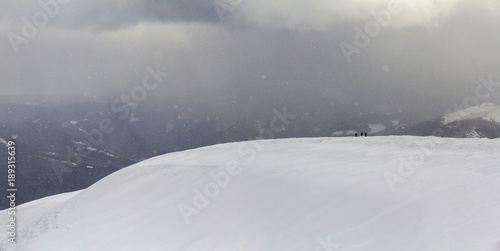 Snow covered Carpathian mountain hills with far away hikers tourists in winter © bilanol