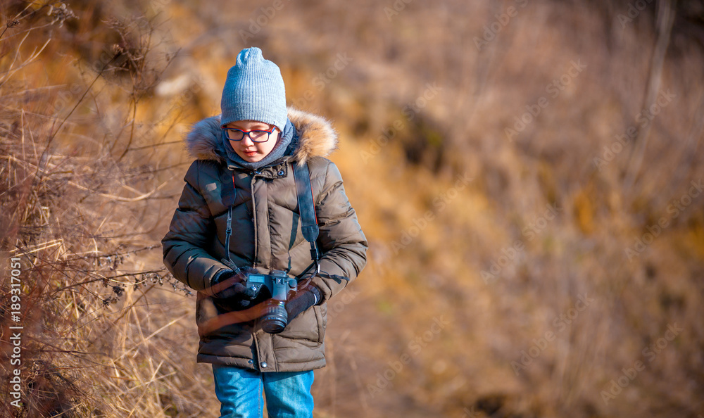 Fototapeta premium Boy with digital camera walking in the nature, hobby concept