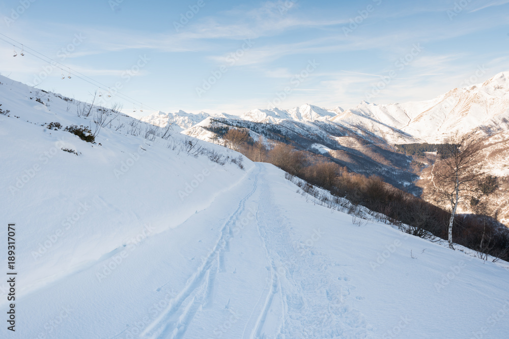 Scenic mountain view on snowy off ski slope in sunny winter day at sunrise outdoor.