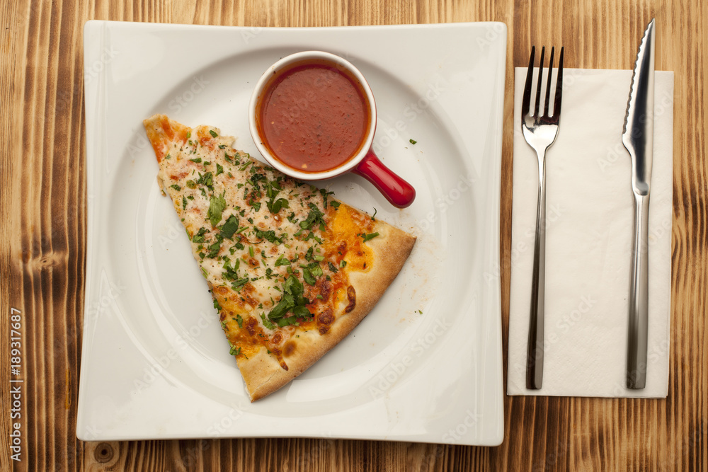 a piece of pizza Apolonia on a plate served with ketchup a piece of pizza Apolonia on a plate served with ketchup