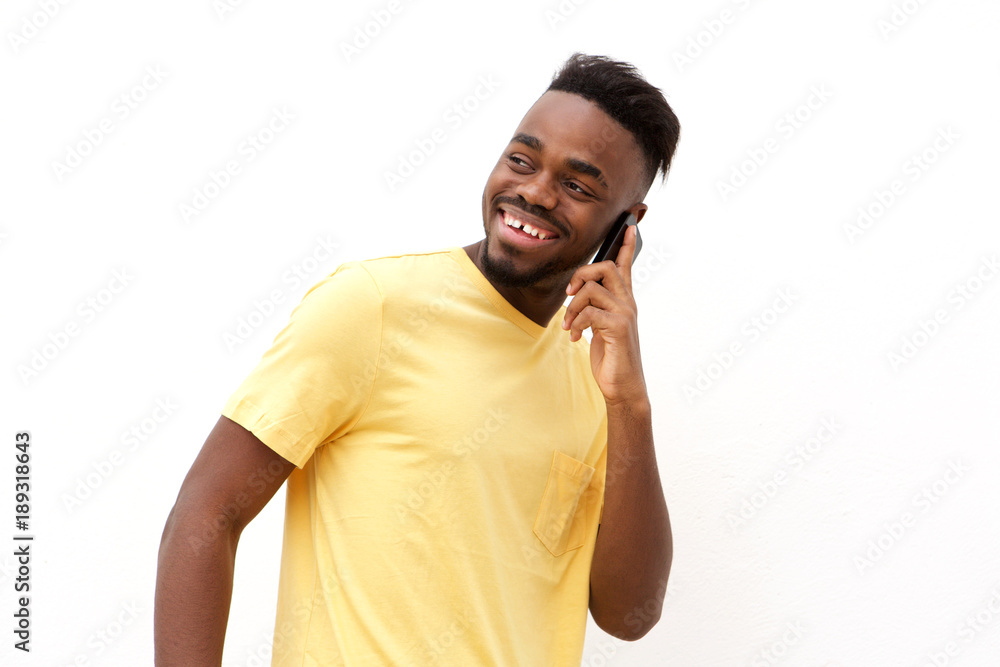 young black man smiling and talking on mobile phone against white background young black man smiling and talking on mobile phone against white background