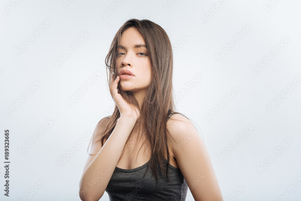 Stressful life. Elegant irresistible pleasant woman standing on the light background while planing arm on the chick and gazing at the camera Stressful life. Elegant irresistible pleasant woman standing on the light background while planing arm on the chick and gazing at the camera