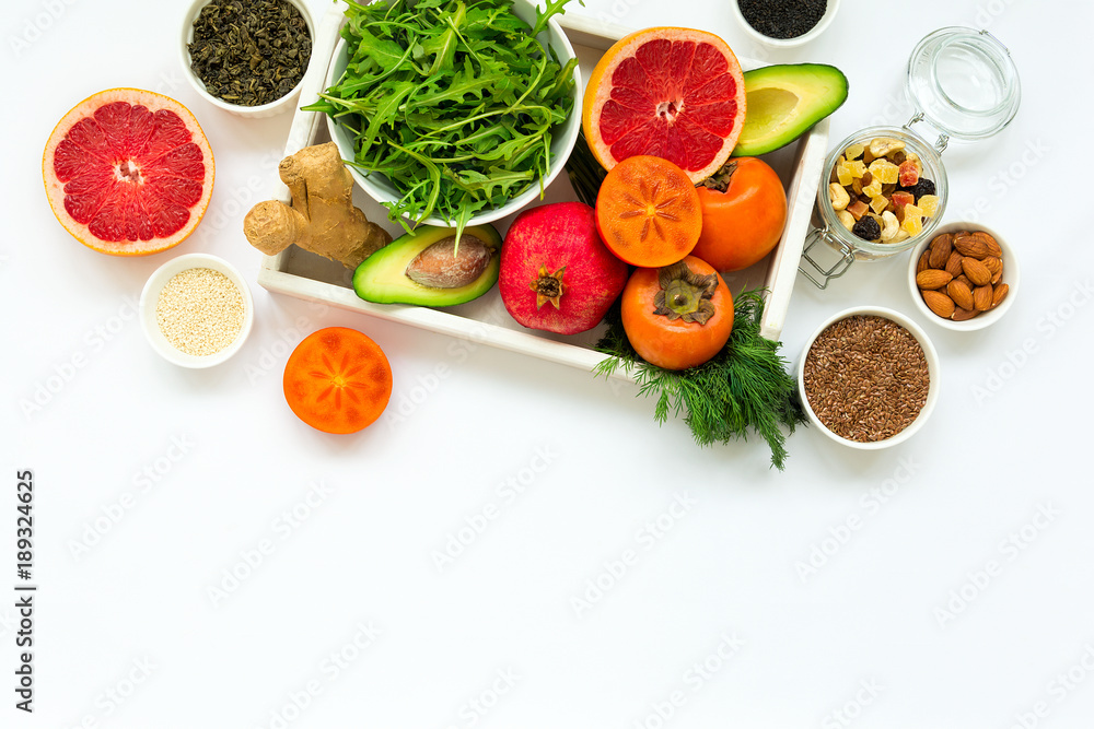 Healthy food in wooden tray: fruits, vegetables, seeds and greens on white background. Flat lay. Top view