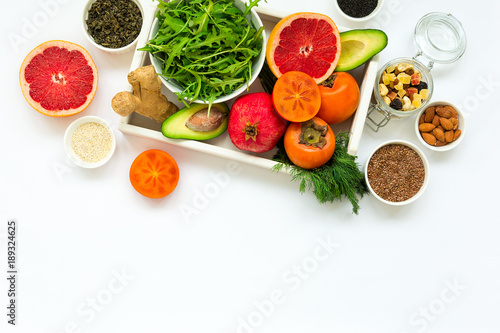 Fototapeta Naklejka Na Ścianę i Meble -  Healthy food in wooden tray: fruits, vegetables, seeds and greens on white background. Flat lay. Top view
