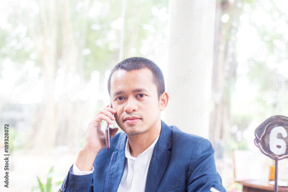 Adult asian businessman in blue suit talking on smartphone Adult asian businessman in blue suit talking on smartphone