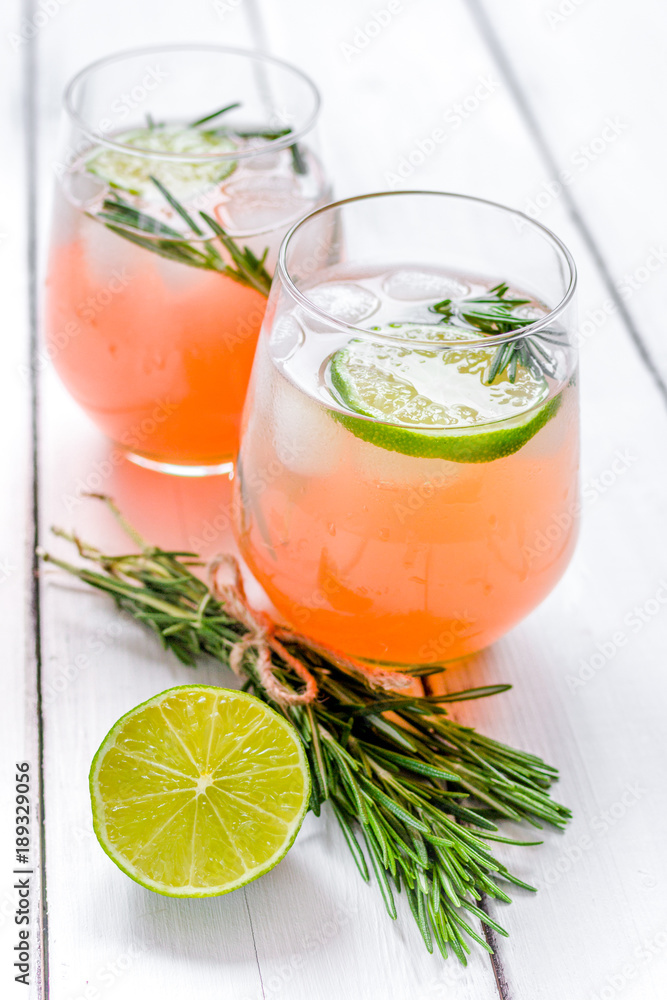 fitness cocktail in glass with lime and rosemary on white table fitness cocktail in glass with lime and rosemary on white table