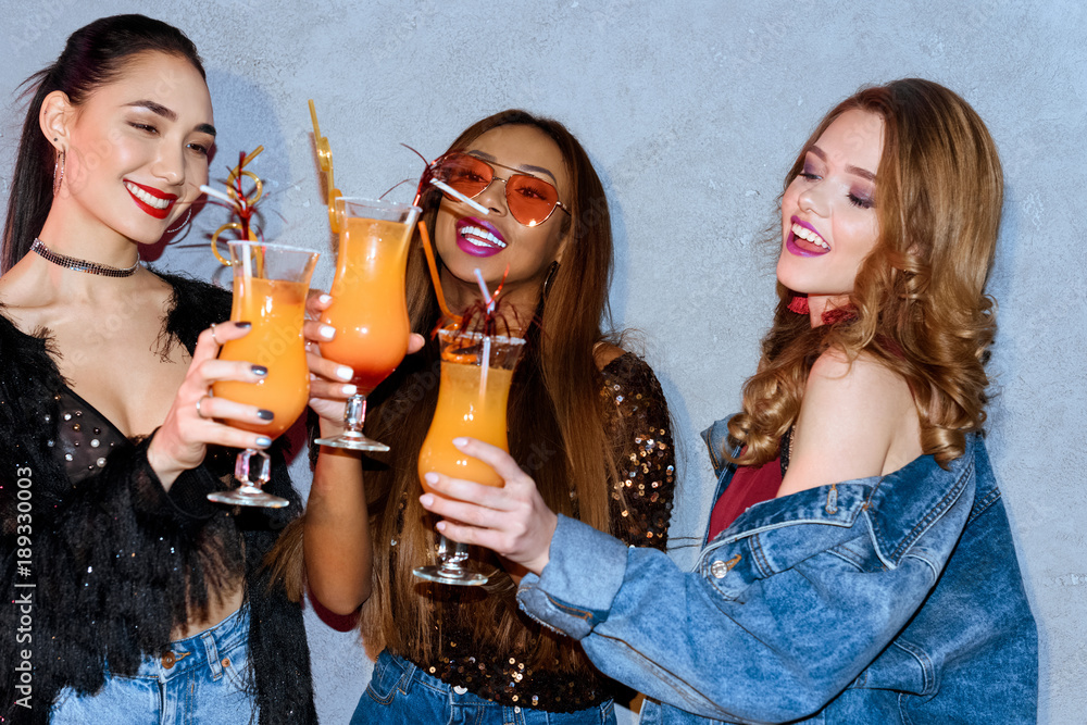 beautiful smiling multiethnic girls clinking glasses at party