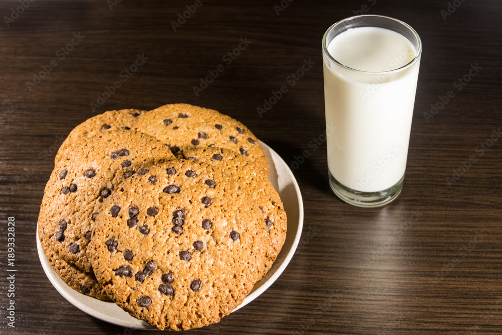Chocolate chip cookies and glass of milk on wooden table Chocolate chip cookies and glass of milk on wooden table