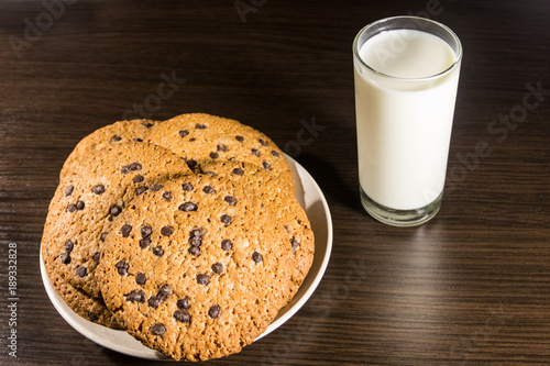 Chocolate chip cookies and glass of milk on wooden table