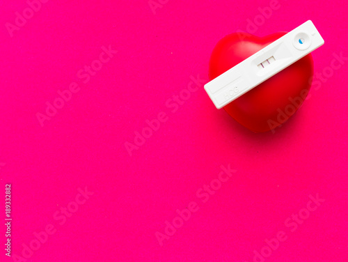 Pregnancy test with a red heart on a red background