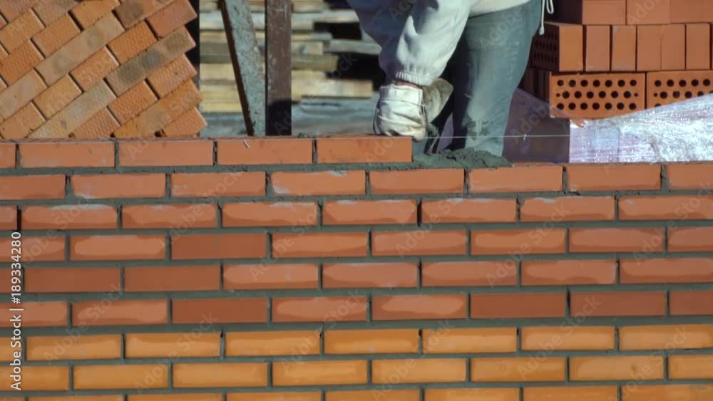 time lapse view of worker builds a wall of bricks in summer day. the builder on a building makes bricklaying. the builder at the construction site makes brickwork. time lapse view of worker builds a wall of bricks in summer day. the builder on a building makes bricklaying. the builder at the construction site makes brickwork.