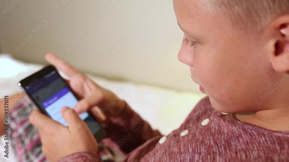 Little kid texting messages at social media application using his black mobile smartphone. Focus at eyes, blurry touch screen. Little kid texting messages at social media application using his black mobile smartphone. Focus at eyes, blurry touch screen.