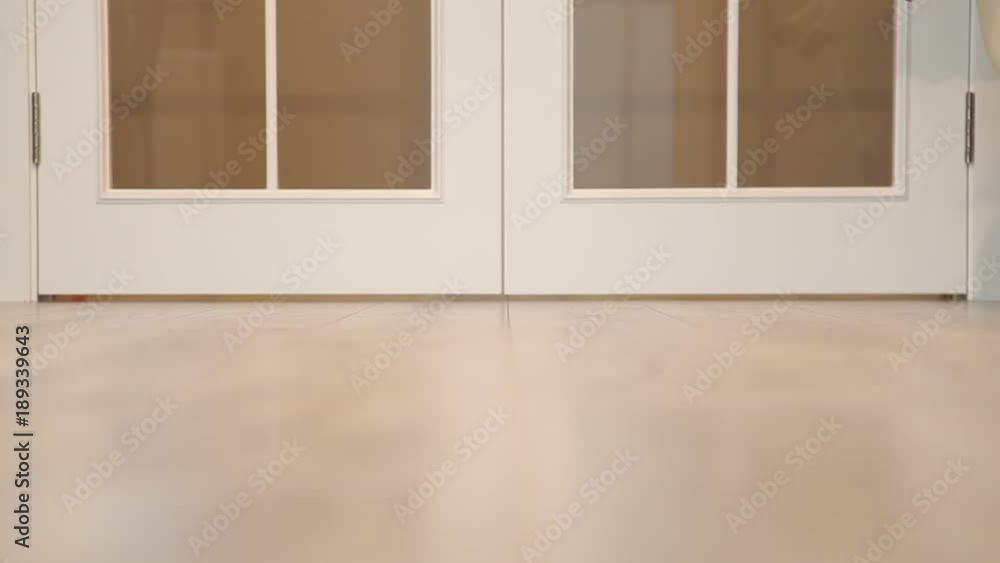 Baby Walking His First Steps. White Wood Door Background.Mother Is Teaching Her Child To Do The First Steps. Close-up On Feet Baby Walking His First Steps. White Wood Door Background.Mother Is Teaching Her Child To Do The First Steps. Close-up On Feet
