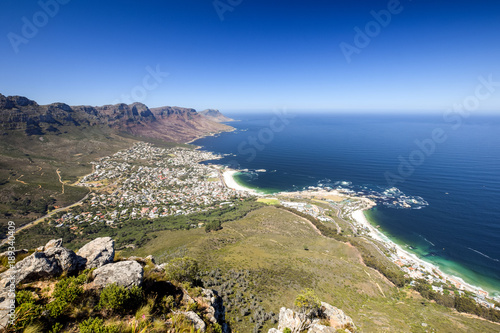 Panorama view of Camps Bay, an affluent suburb of Cape Town, Western Cape, South Africa, seen from the summit of Lion's Head mountain in Cape Town. Twelve apostles mountain range in the background.