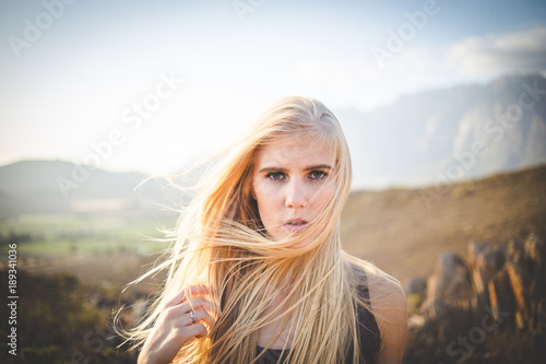 Portrait of a beautiful blond female model in a natural setting with stunning back light