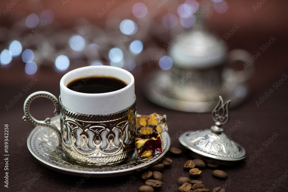 Fototapeta premium Traditional Turkish coffee in traditional metal cup on brown background with bokeh