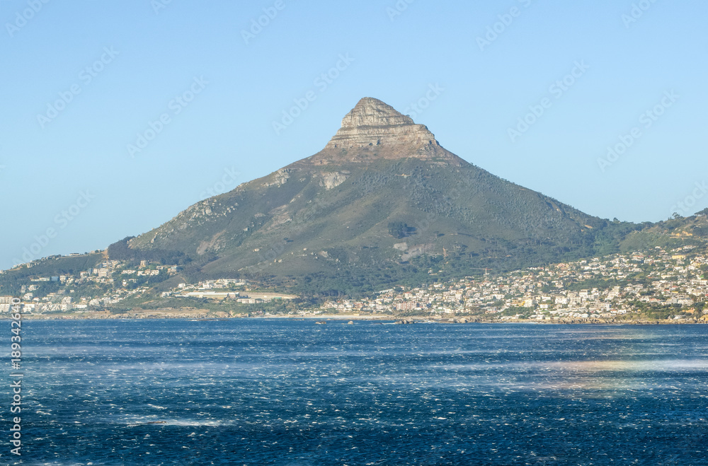 Beautiful view of the affluent towns of Camps Bay and Clifton Beach, both parts of Cape Town, South Africa. Majestic Lion's Head mountain, a famous tourist destination, in the background. 