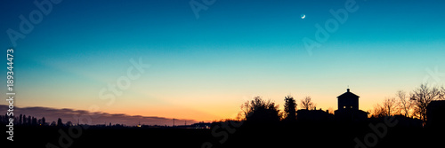 church silhouette at sunset with crescent moon - italian landscape panorama 