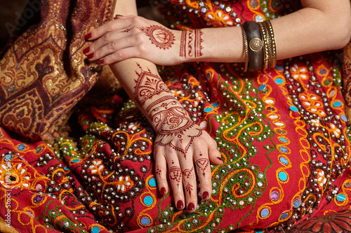 Mehendi on his hands against the backdrop of a national Indian costume. Close-up.