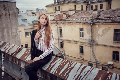 A young red-haired girl in a business suit is walking along a beautiful old town. St.Petersburg © YURII Seleznov