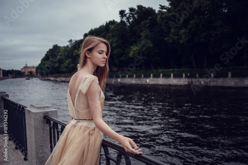 A young red-haired girl in a delicate peach dress is walking along a beautiful old town. St.Petersburg © YURII Seleznov