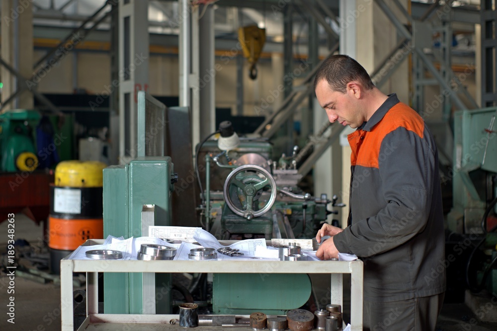 metalworking industry: factory man worker in uniform working on lathe machine in workshop metalworking industry: factory man worker in uniform working on lathe machine in workshop