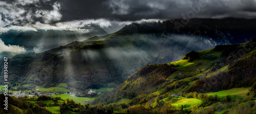 Sun rays lighting through the clouds in high Pyrenees, sunrise, green valley