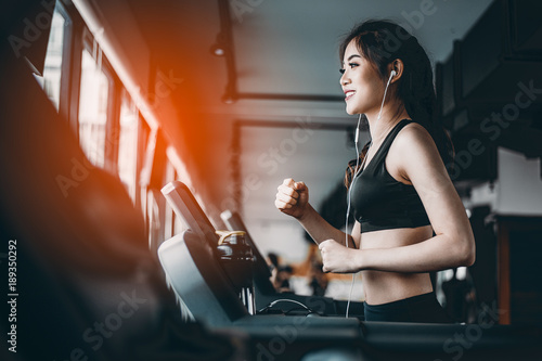 Portrait of Fitness woman running on treadmill in gym listening to music.exercising concept.fitness and healthy lifestyle. © Day Of Victory Stu.