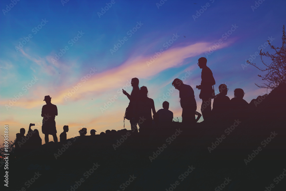 Silhouettes of people standing on the hill watching city on dusk Silhouettes of people standing on the hill watching city on dusk