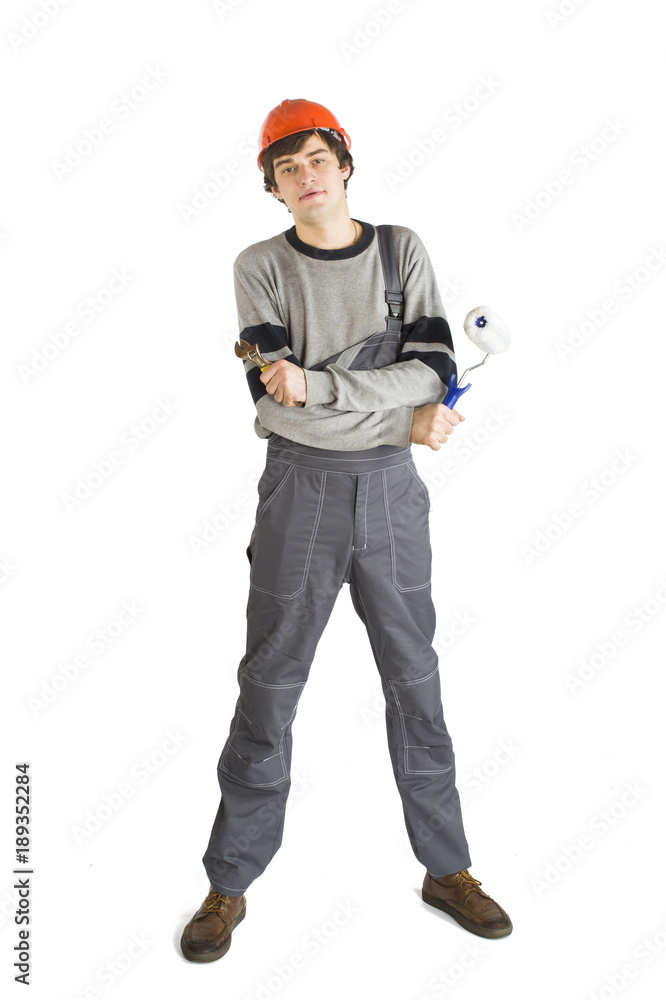 A young man in working grey clothes and orange hard helmet painting the walls in the room. A young man in working grey clothes and orange hard helmet painting the walls in the room.