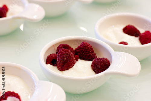 Fresh raspberry berries with whipped cream in serving white plates