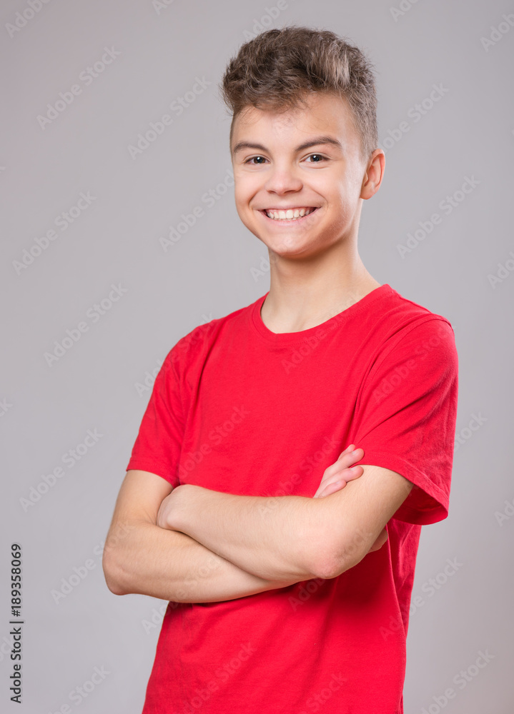 Half-length emotional portrait of caucasian teen boy wearing red t-shirt.  Funny teenager with arms folded, on gray background. Handsome child looking  at camera. Stock Photo | Adobe Stock