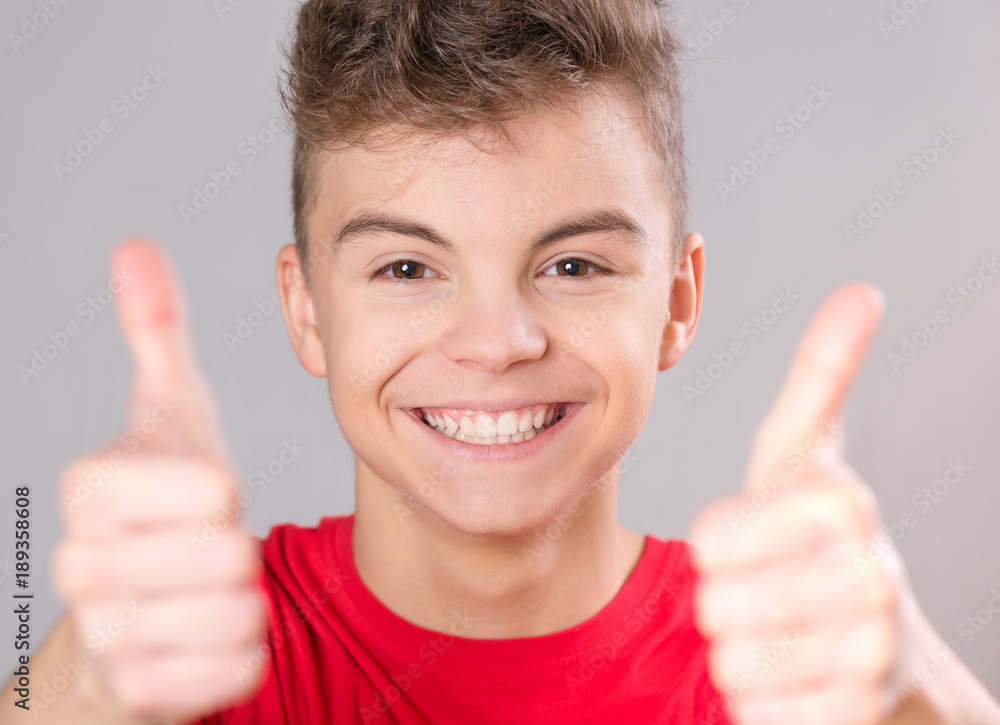 Close-up emotional portrait of caucasian teen boy wearing red t-shirt. Funny teenager making thumbs up gesture, isolated on white background. Handsome child laughing looking very happy. Close-up emotional portrait of caucasian teen boy wearing red t-shirt. Funny teenager making thumbs up gesture, isolated on white background. Handsome child laughing looking very happy.