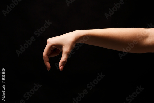 Female hand picking up something, cutout on black