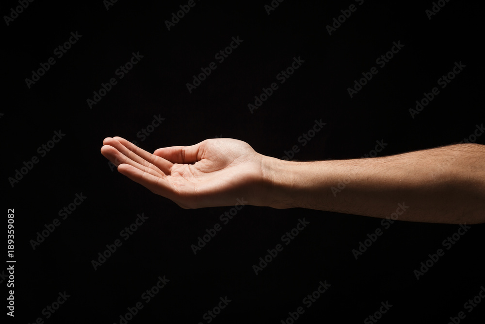 Man holding palm open isolated on black