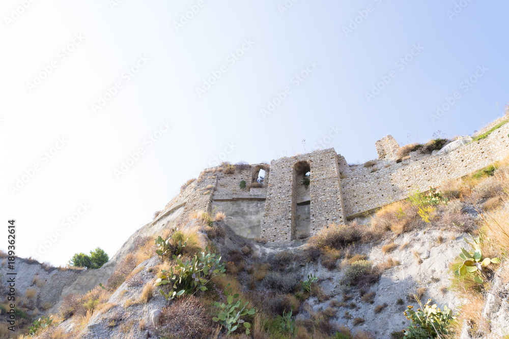 View from below of the walls of ancient castle of Roccella Ionica (Calabria) with blue sky