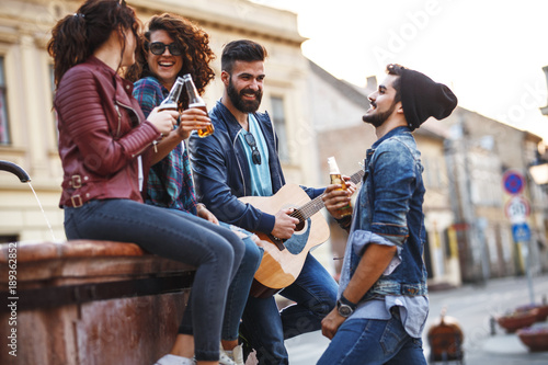 Group of young friends hangout on city square .