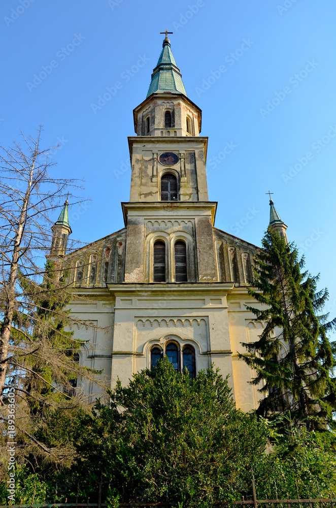 old church on blue sky with trees around, front view