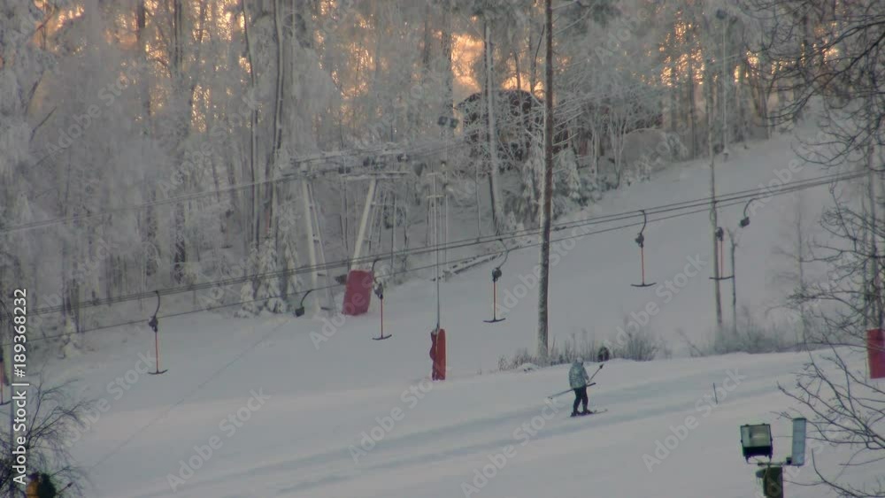 Tourists Skiers climb the slope the ski lifts at sunset. Winter sport and active leisure - skiing on the snowy hills at the resort. Tourists Skiers climb the slope the ski lifts at sunset. Winter sport and active leisure - skiing on the snowy hills at the resort.