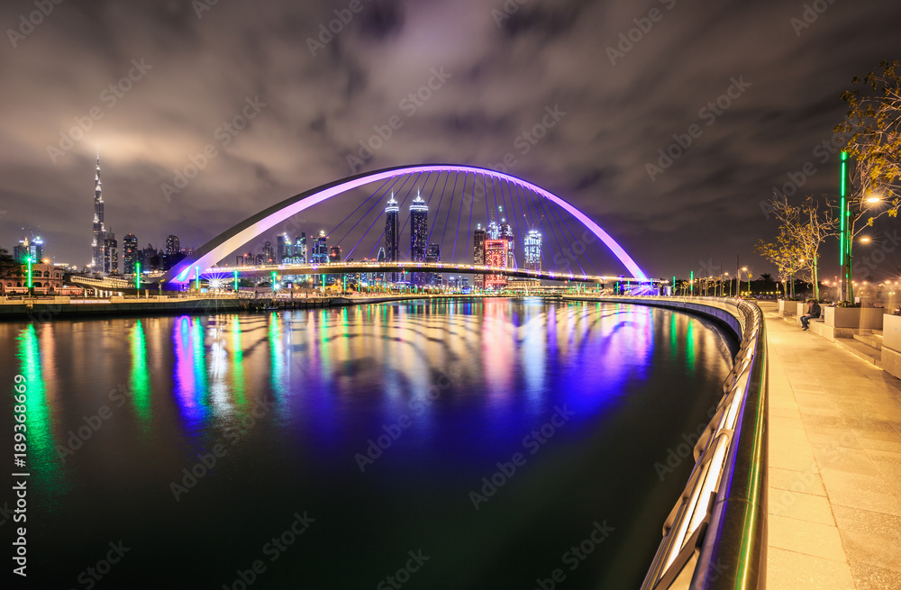 Obraz premium Bridge over water canal with reflection and Dubai skyline, United Arab Emirates