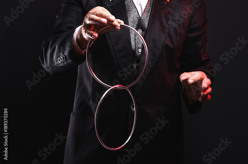 Magician shows trick with metal rings. Manipulation with props. Sleight of hand.