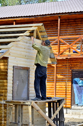 Carpenter checks the straight line before fastening metal roofing to the rafters of a barn.