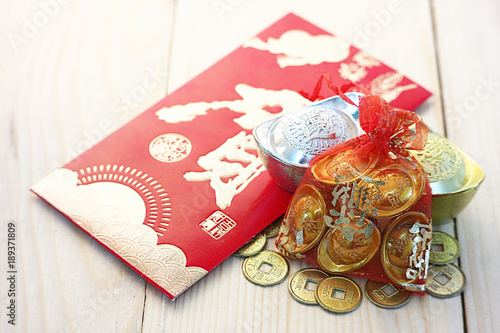Gold and money coin on red pocket " Ang Pao" with background wood plate.Chinese word mean " Happy "