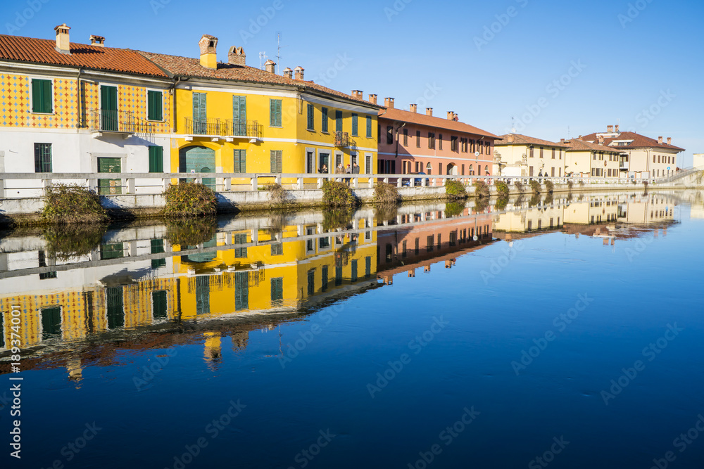 Naviglio Grande canal waterway passes near the historic and colorful buildings of Gaggiano (Milan, Italy)