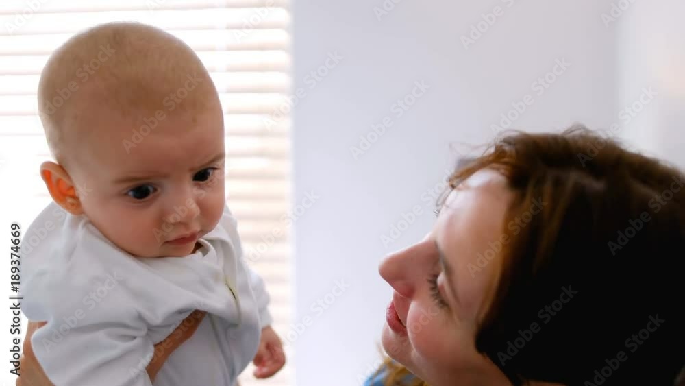 Young mother holding and kissing her baby at home Young mother holding and kissing her baby at home