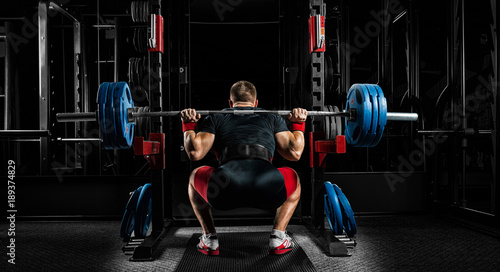 Quadro su tela Professional athlete sits with a barbell on his shoulders and prepares to stand with her